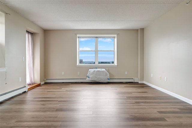 empty room with baseboard heating, wood-type flooring, and a textured ceiling