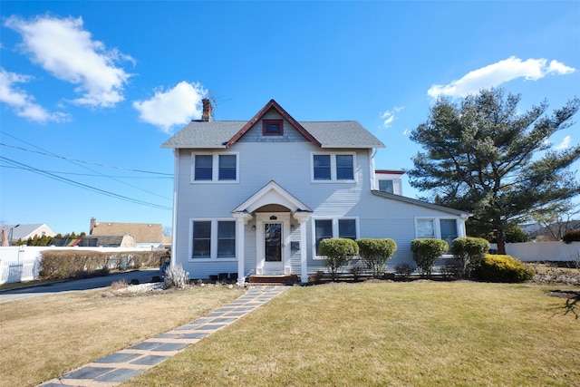 view of front of property with a front lawn, a chimney, and fence