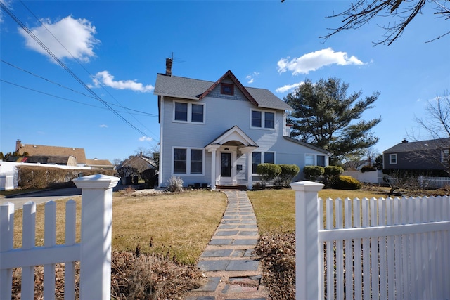 view of front of home featuring a fenced front yard, a chimney, and a front lawn