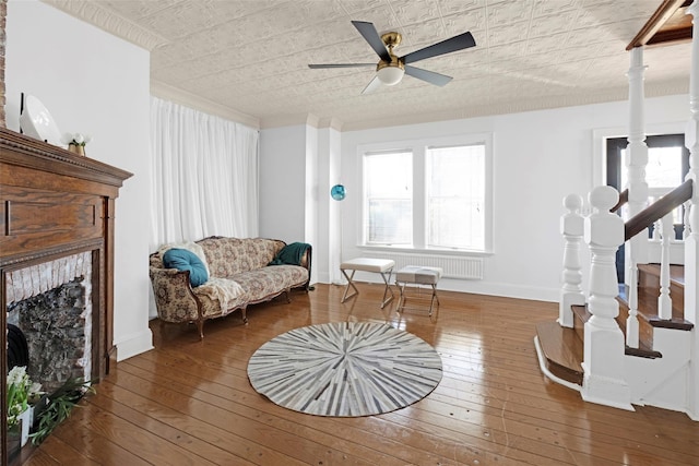 sitting room with baseboards, hardwood / wood-style flooring, ceiling fan, stairs, and a fireplace