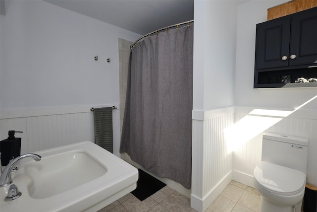 full bathroom featuring a wainscoted wall, toilet, and tile patterned floors