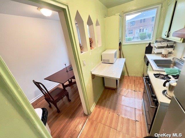 kitchen with sink, white appliances, and light hardwood / wood-style flooring