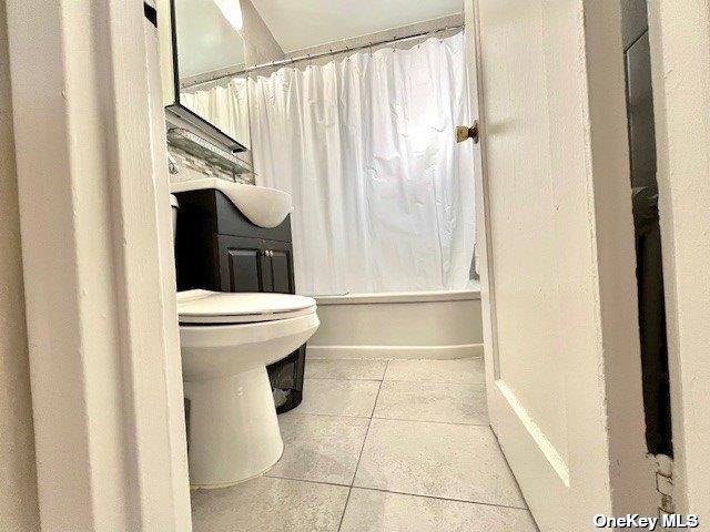 bathroom with tile patterned flooring, shower / bath combo, and toilet