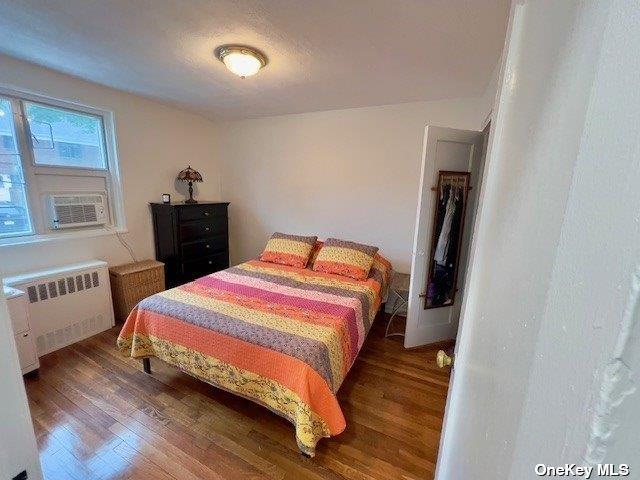 bedroom with radiator, dark wood-type flooring, and cooling unit