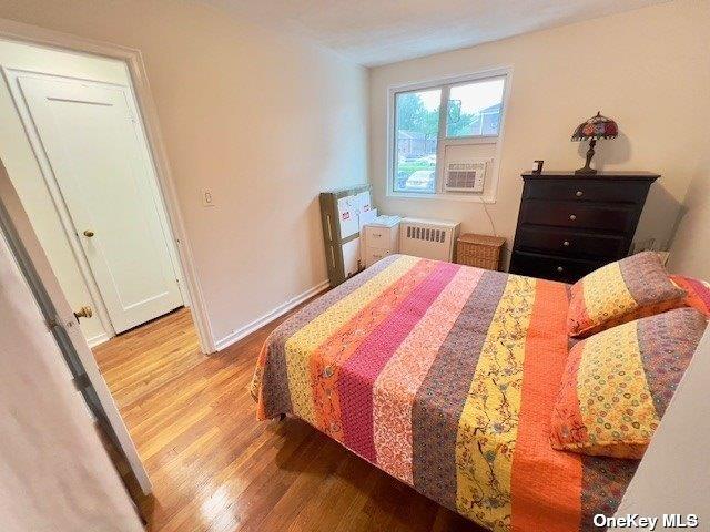 bedroom with radiator heating unit and light hardwood / wood-style flooring