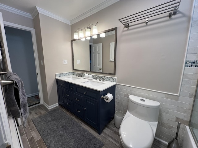 bathroom with ornamental molding, toilet, vanity, and tile walls