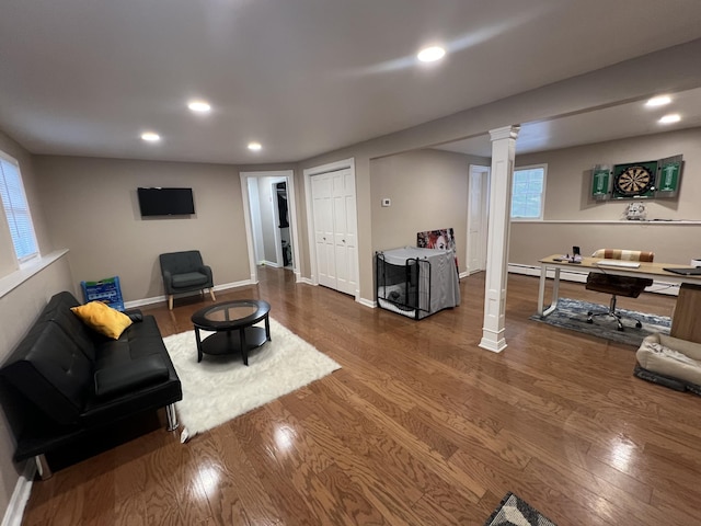 living room with hardwood / wood-style flooring, a baseboard heating unit, and ornate columns