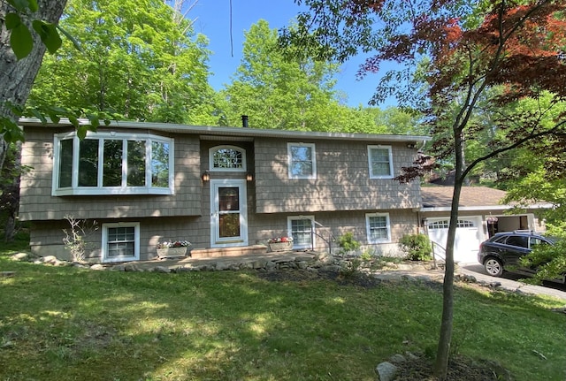 raised ranch featuring a garage and a front lawn