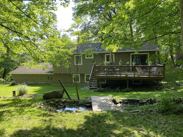 rear view of house with a wooden deck and a lawn