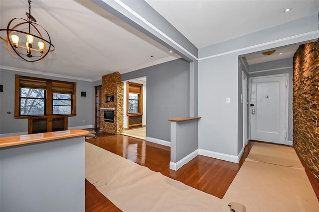 interior space featuring an inviting chandelier, hardwood / wood-style flooring, a fireplace, and ornamental molding