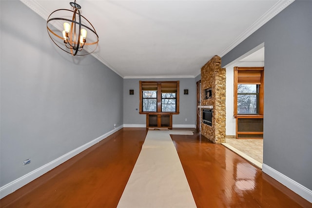 unfurnished living room with crown molding, a notable chandelier, a stone fireplace, and dark wood-type flooring