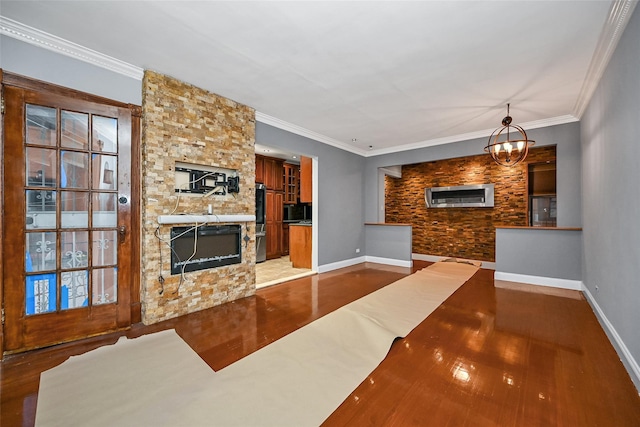 living room with ornamental molding, a stone fireplace, hardwood / wood-style floors, and a notable chandelier