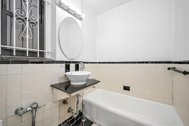 bathroom featuring a bath, sink, and tile walls