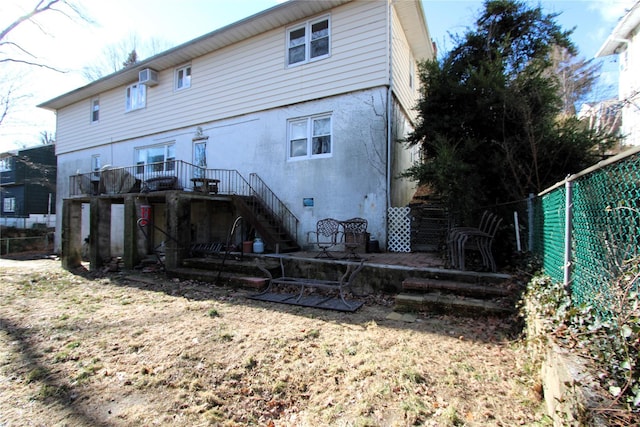 rear view of property with a wall mounted AC and a lawn