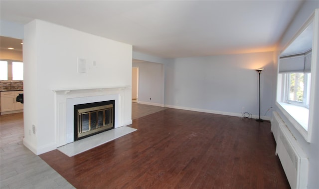 unfurnished living room featuring radiator heating unit and dark hardwood / wood-style floors