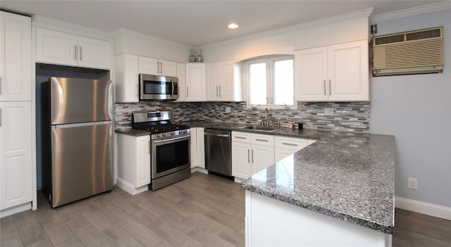 kitchen featuring sink, appliances with stainless steel finishes, white cabinetry, dark stone countertops, and ornamental molding