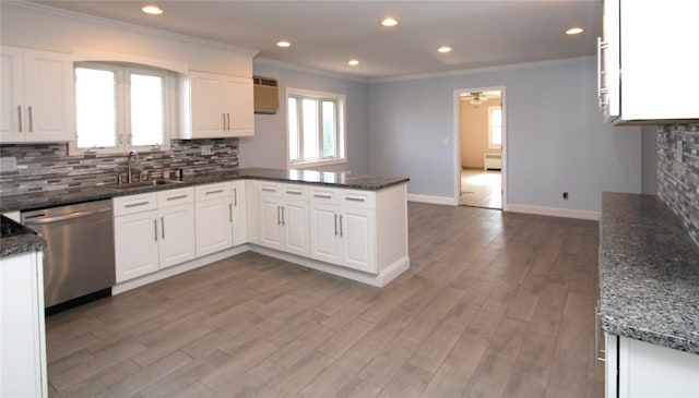 kitchen featuring sink, dishwasher, kitchen peninsula, dark stone counters, and white cabinets