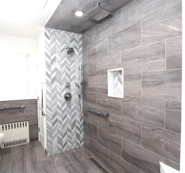 bathroom with tiled shower, radiator heating unit, and toilet