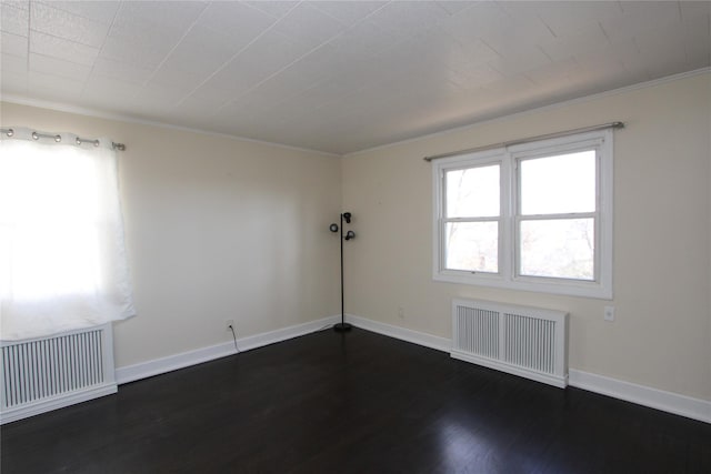 empty room featuring crown molding, dark wood-type flooring, and radiator heating unit