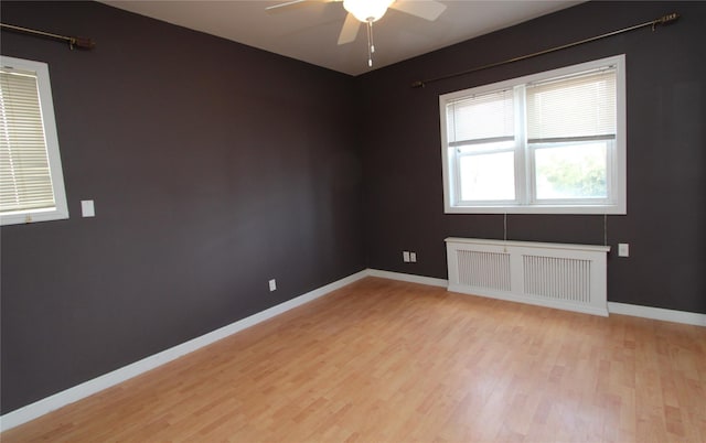 empty room featuring ceiling fan, radiator heating unit, and light hardwood / wood-style floors