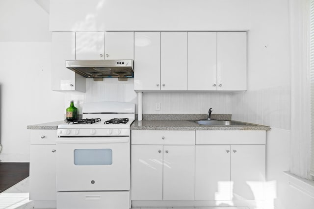 kitchen with white gas range, sink, and white cabinets