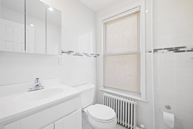 bathroom featuring tile walls, vanity, radiator heating unit, and toilet