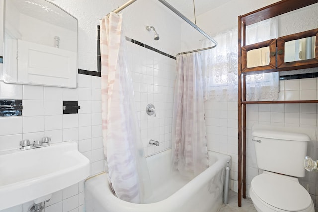 full bathroom featuring toilet, sink, tile walls, and shower / bath combo with shower curtain