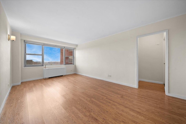 spare room with radiator heating unit and light hardwood / wood-style flooring