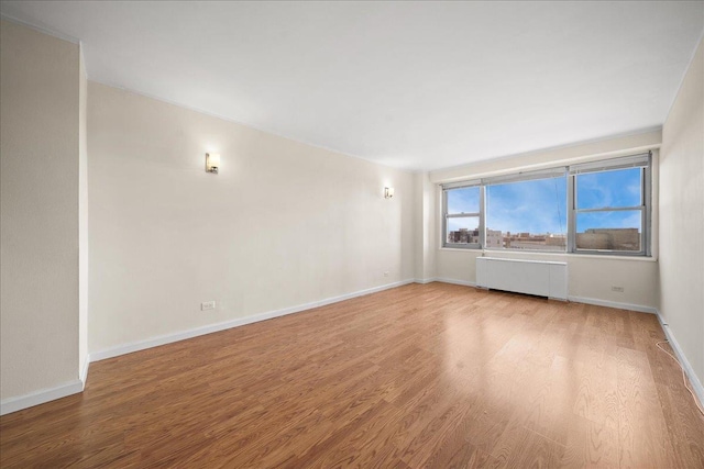 empty room featuring radiator and hardwood / wood-style flooring