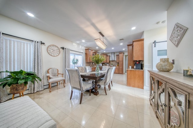 dining space featuring a barn door and light tile patterned floors