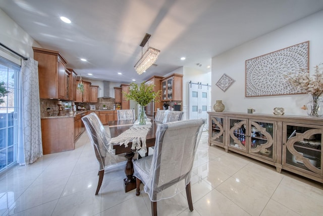 dining area with a barn door and light tile patterned floors