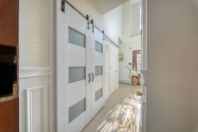 hall with a barn door, a high ceiling, and light tile patterned floors