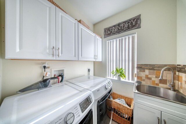 washroom with cabinets, washing machine and dryer, and sink