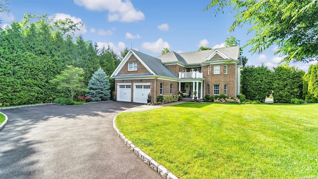 view of front of home featuring a garage, a balcony, and a front yard