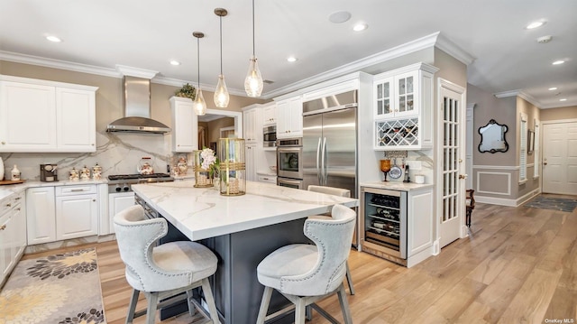 kitchen with white cabinetry, wall chimney exhaust hood, stainless steel appliances, and a center island