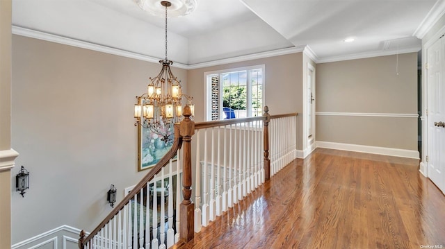 corridor with hardwood / wood-style floors, crown molding, and a chandelier