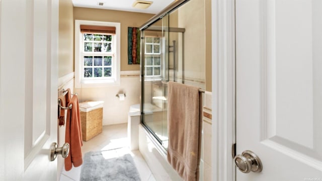 bathroom featuring tile patterned flooring, enclosed tub / shower combo, and tile walls