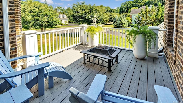 wooden deck featuring a fire pit and a lawn