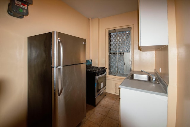 kitchen featuring light tile patterned floors, a sink, stainless steel appliances, light countertops, and white cabinetry