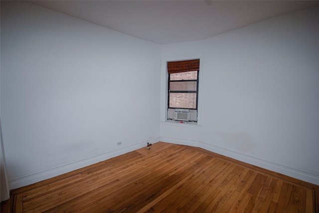 empty room featuring baseboards, wood-type flooring, and cooling unit