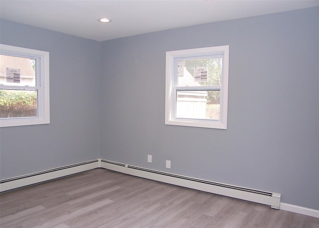 empty room with a baseboard radiator and light hardwood / wood-style flooring