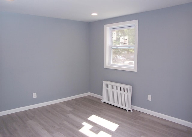 unfurnished room featuring radiator and light wood-type flooring