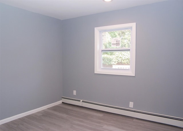 spare room with a baseboard heating unit and light hardwood / wood-style floors