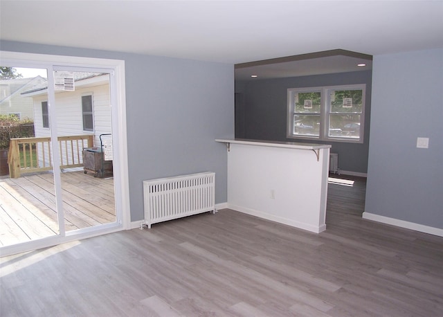 unfurnished living room featuring dark hardwood / wood-style flooring, radiator heating unit, and a healthy amount of sunlight