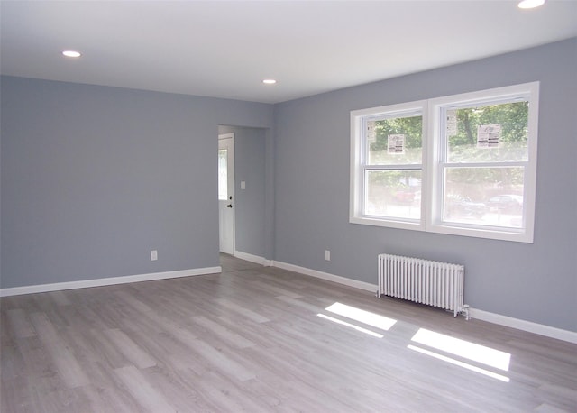 spare room with radiator heating unit and light wood-type flooring