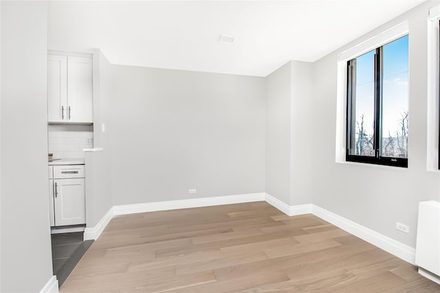 unfurnished room with radiator heating unit and light wood-type flooring