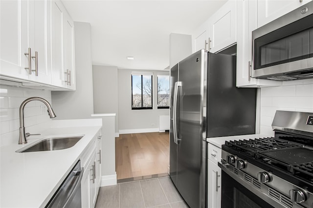 kitchen with sink, decorative backsplash, white cabinets, and appliances with stainless steel finishes