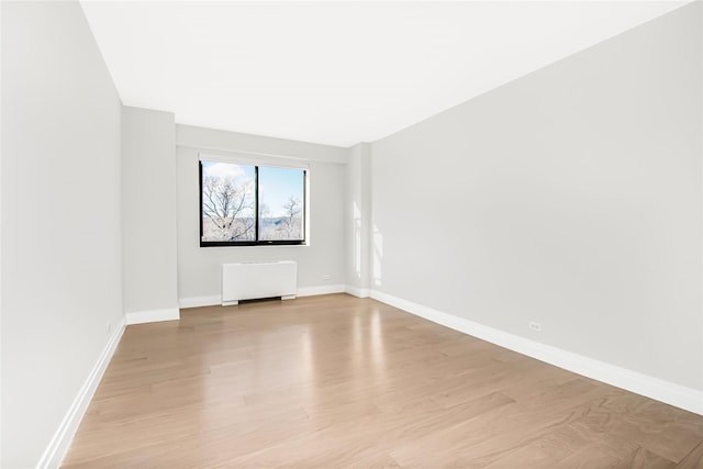 spare room featuring radiator and light hardwood / wood-style floors