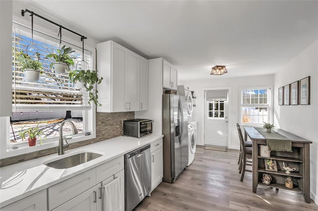 kitchen with sink, stainless steel appliances, tasteful backsplash, white cabinets, and light wood-type flooring