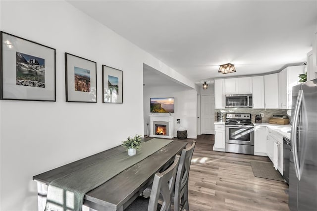 kitchen with white cabinetry, stainless steel appliances, dark hardwood / wood-style flooring, and decorative backsplash